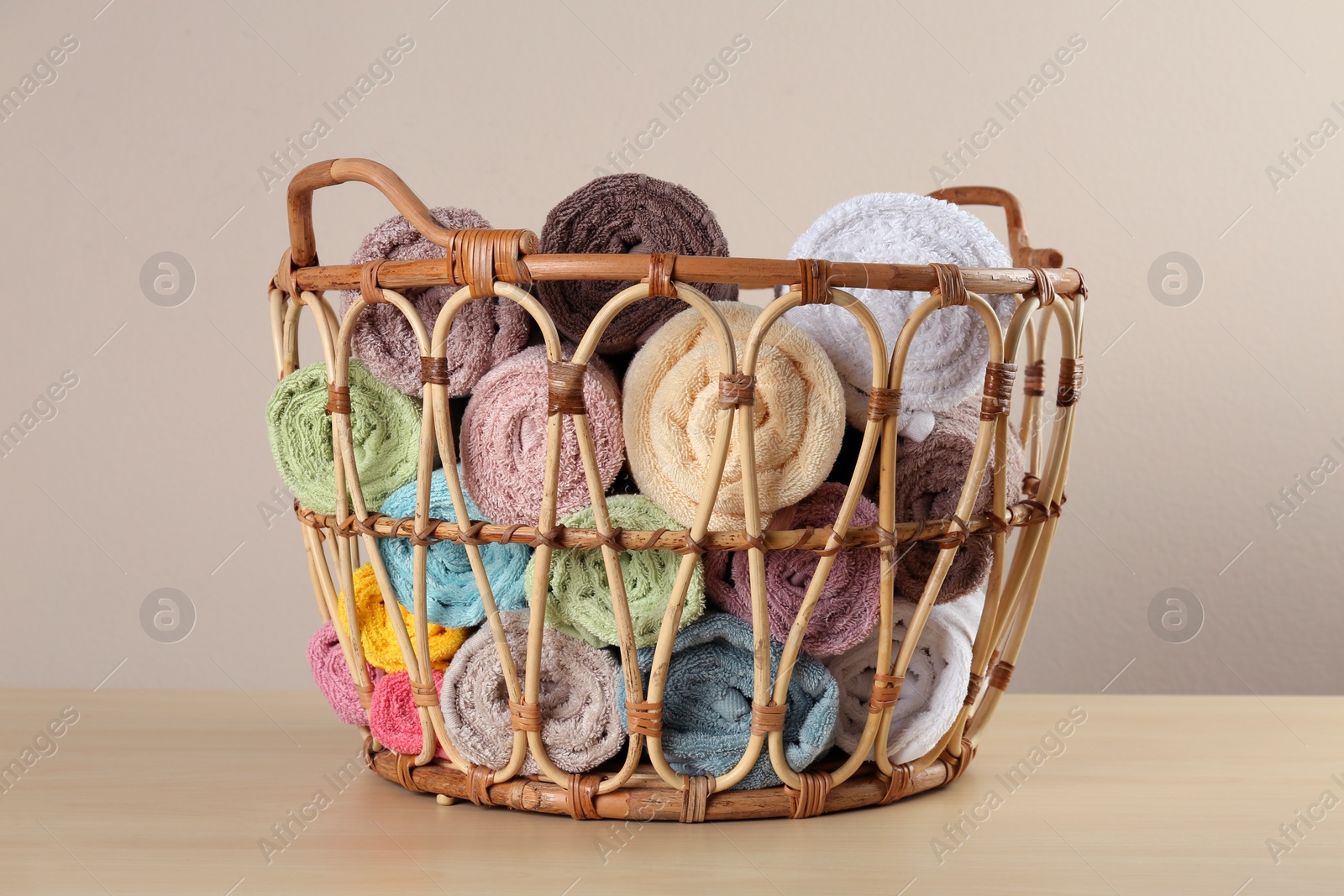 Photo of Wicker basket with clean soft towels on wooden table