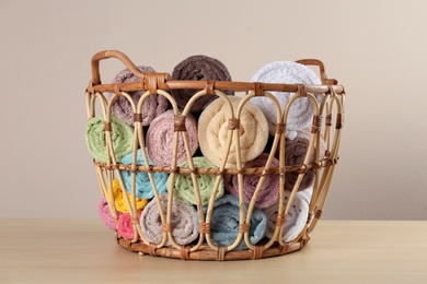 Photo of Wicker basket with clean soft towels on wooden table