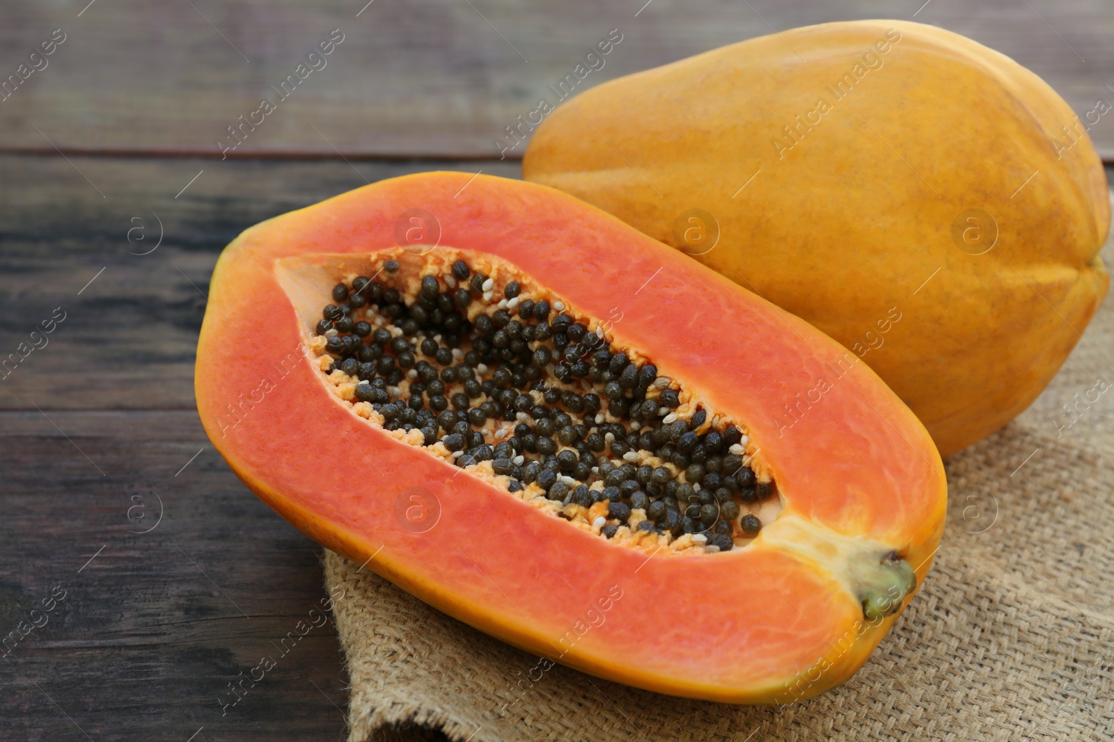 Photo of Tasty cut and whole papaya fruits on wooden table, closeup