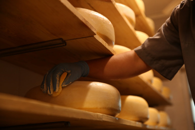 Photo of Worker coating cheese with wax in factory warehouse, closeup