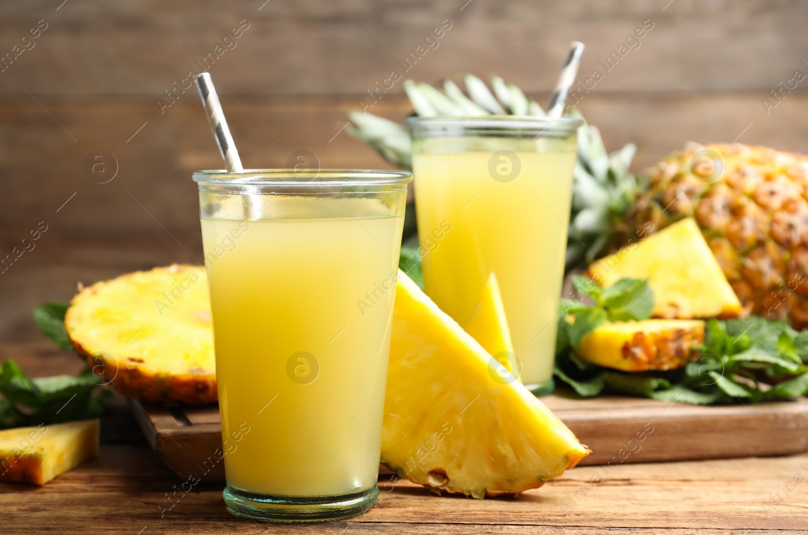 Photo of Delicious pineapple juice and fresh fruit on wooden table