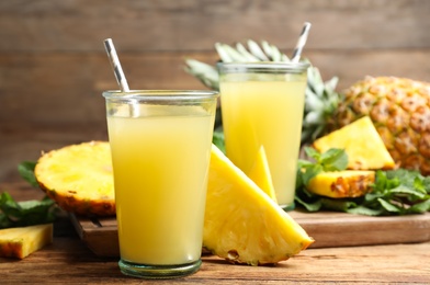 Photo of Delicious pineapple juice and fresh fruit on wooden table