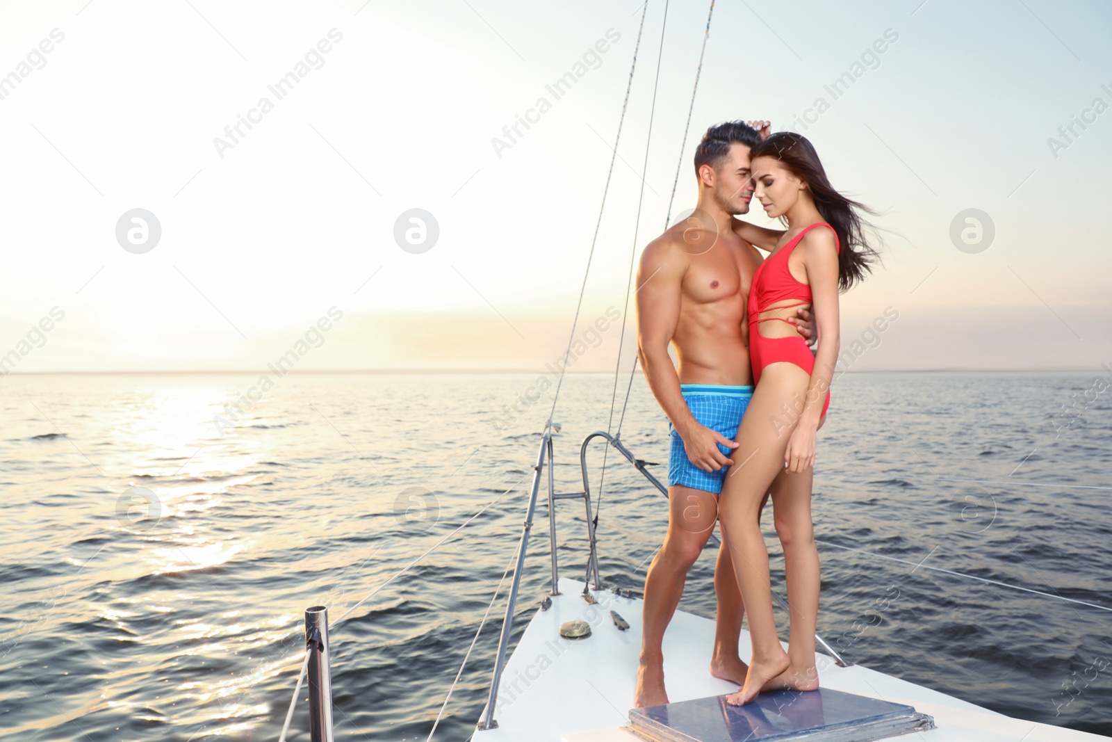 Photo of Young man and his beautiful girlfriend in bikini on yacht. Happy couple during sea trip