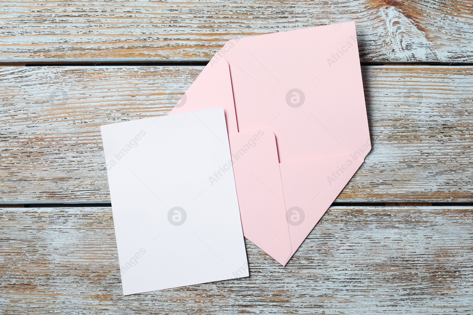 Photo of Blank sheet of paper and letter envelope on wooden rustic table, top view. Space for text