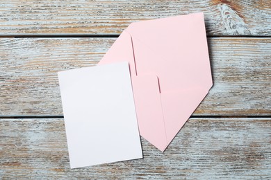 Blank sheet of paper and letter envelope on wooden rustic table, top view. Space for text