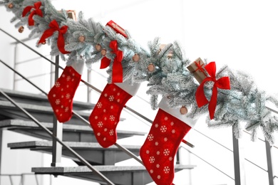 Photo of Santa stockings and garland on railing indoors. Christmas decor idea