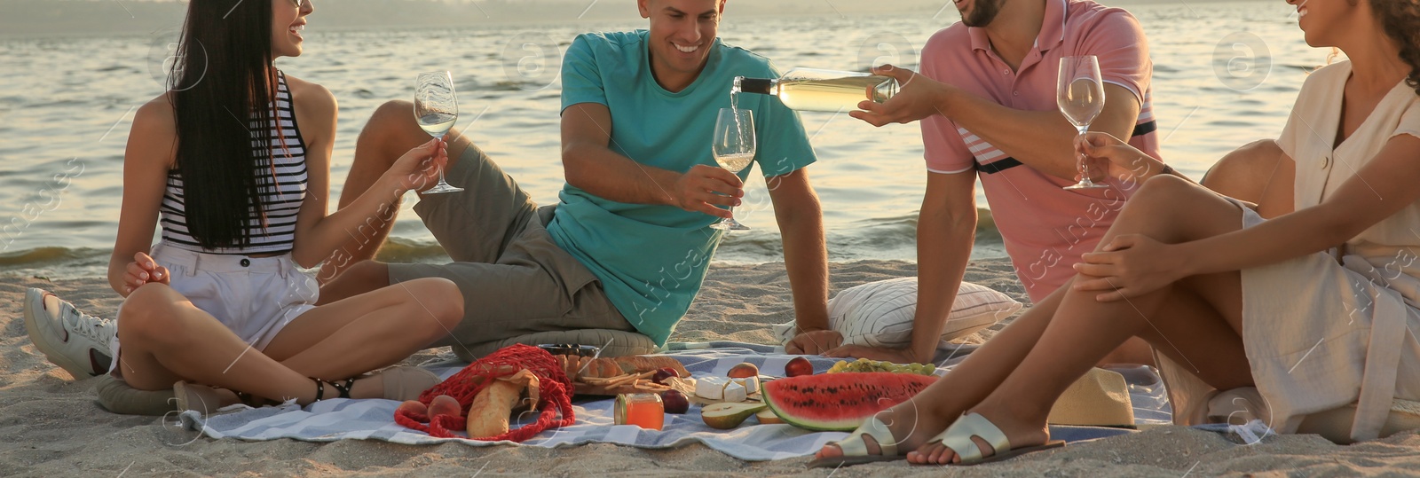 Image of Group of friends having picnic outdoors at sunset. Banner design