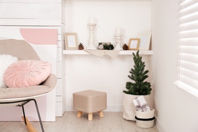 Stylish room interior with rocking chair, wall shelves and beautiful Christmas decor