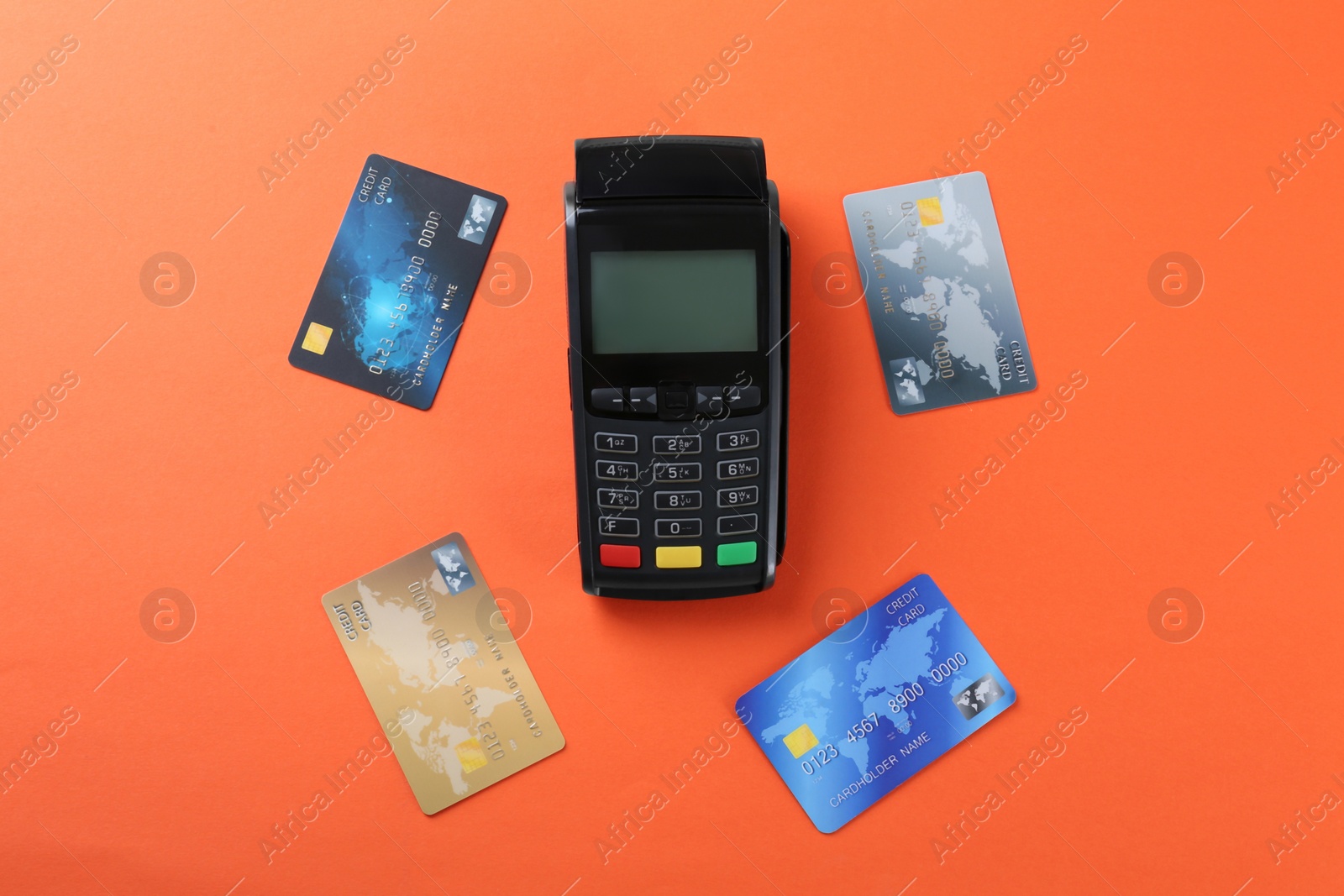 Photo of New modern payment terminal and credit cards on orange background, flat lay
