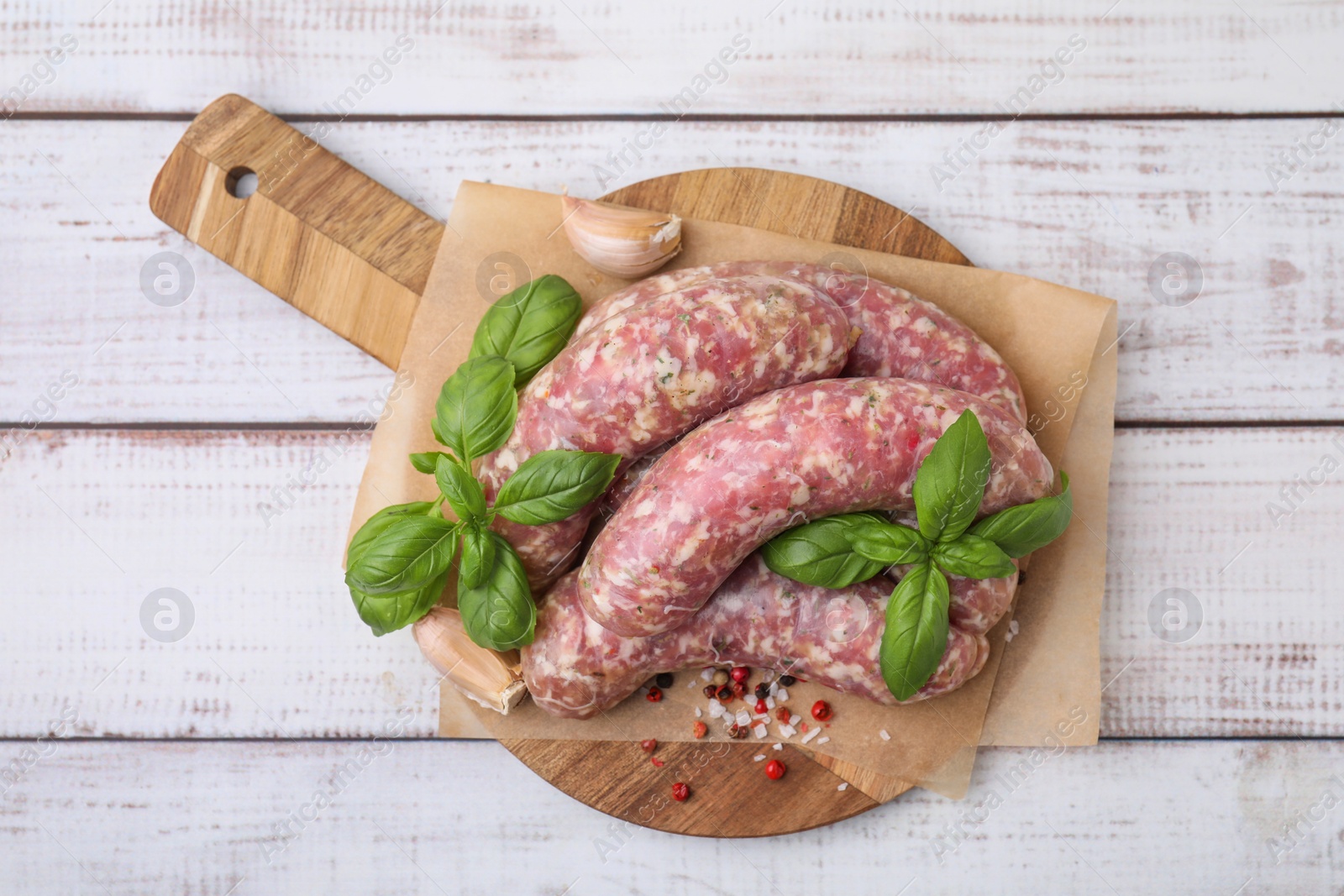 Photo of Raw homemade sausages and different spices on white wooden table, top view