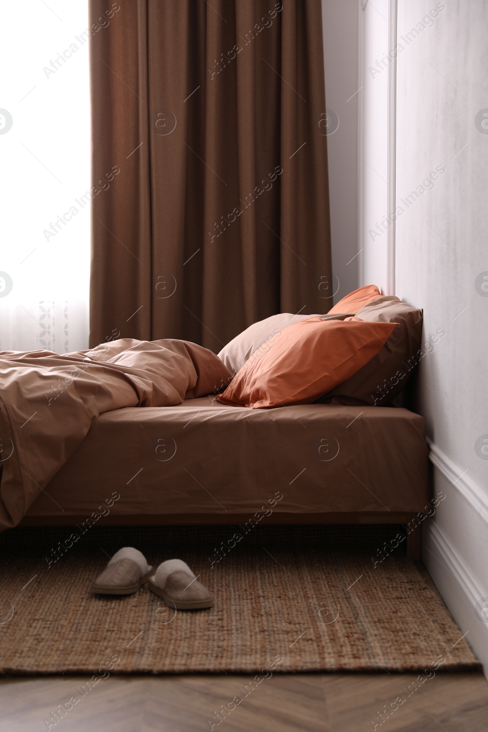 Photo of Bed with orange and brown linens in stylish room