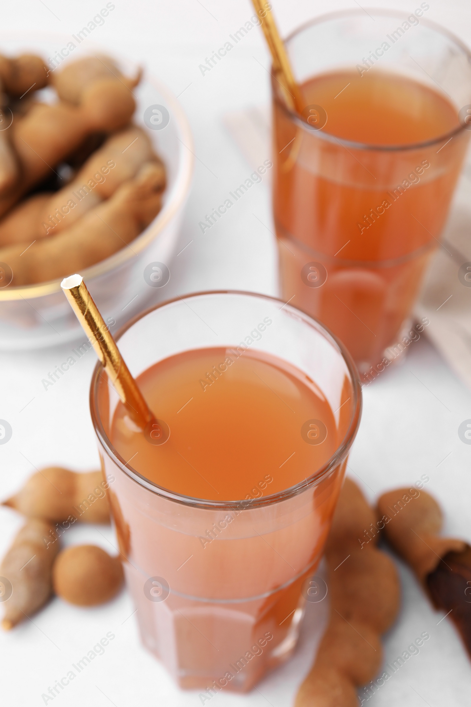 Photo of Tamarind juice and fresh fruits on white table, closeup