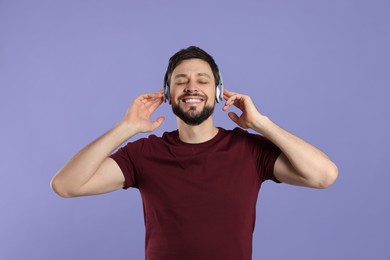 Photo of Happy man in headphones enjoying music on purple background