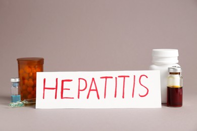 Photo of Word Hepatitis, vials and bottles of pills on beige background