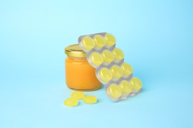Cough drops and honey on light blue background