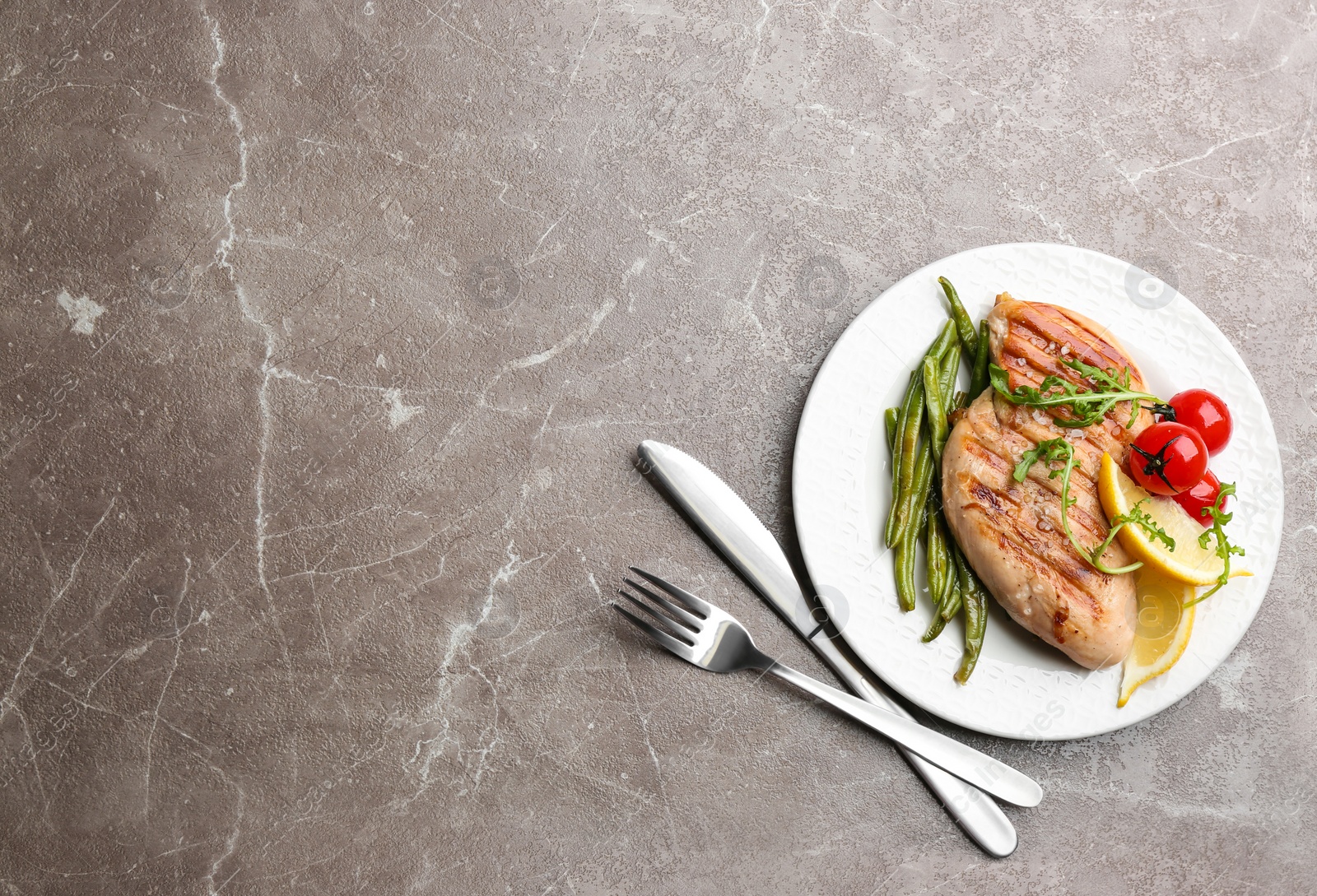 Photo of Tasty grilled chicken fillet served on brown marble table, flat lay. Space for text