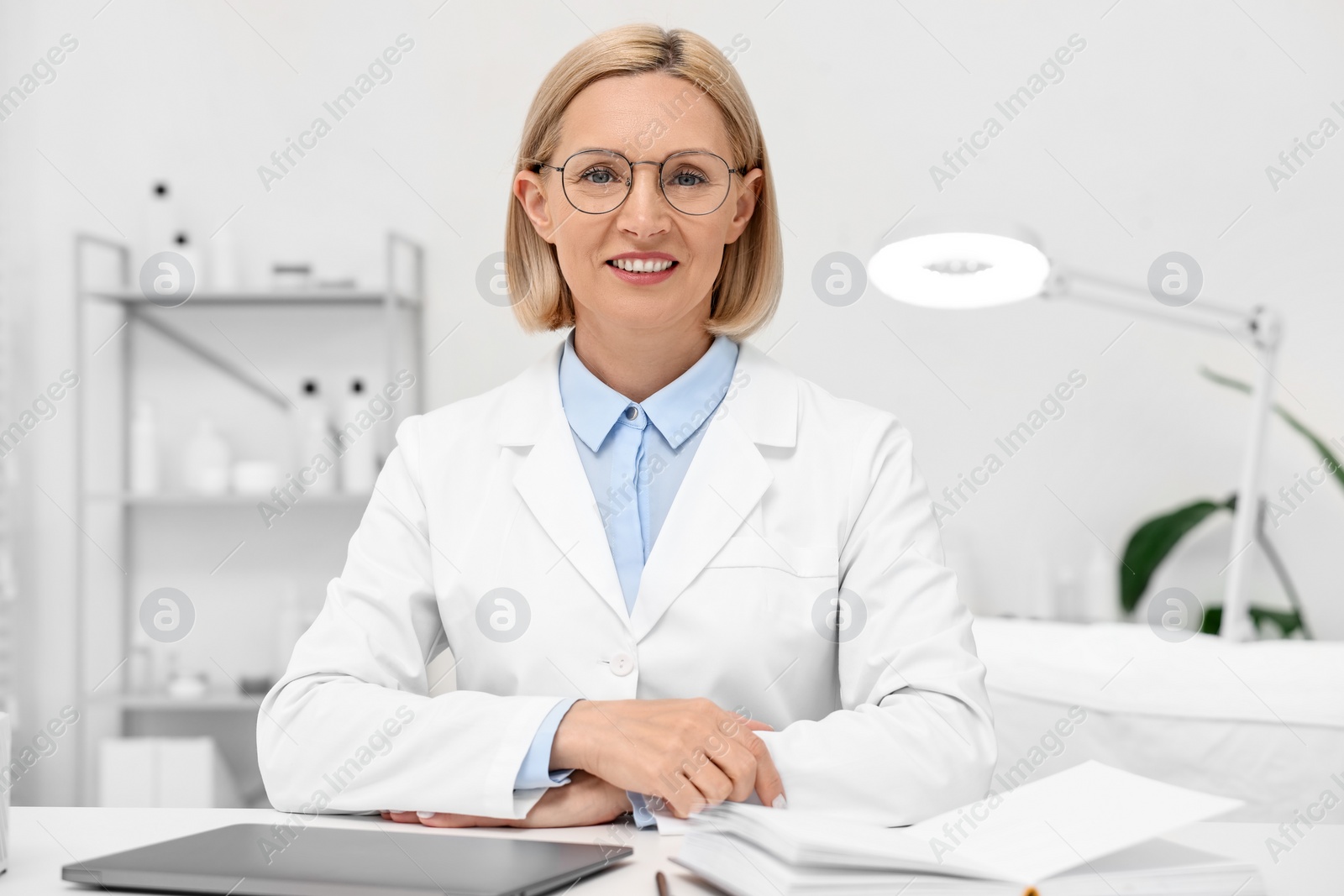 Photo of Portrait of happy dermatologist at white table in clinic