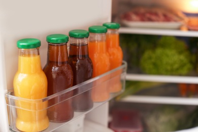 Photo of Open refrigerator with bottles of different juices