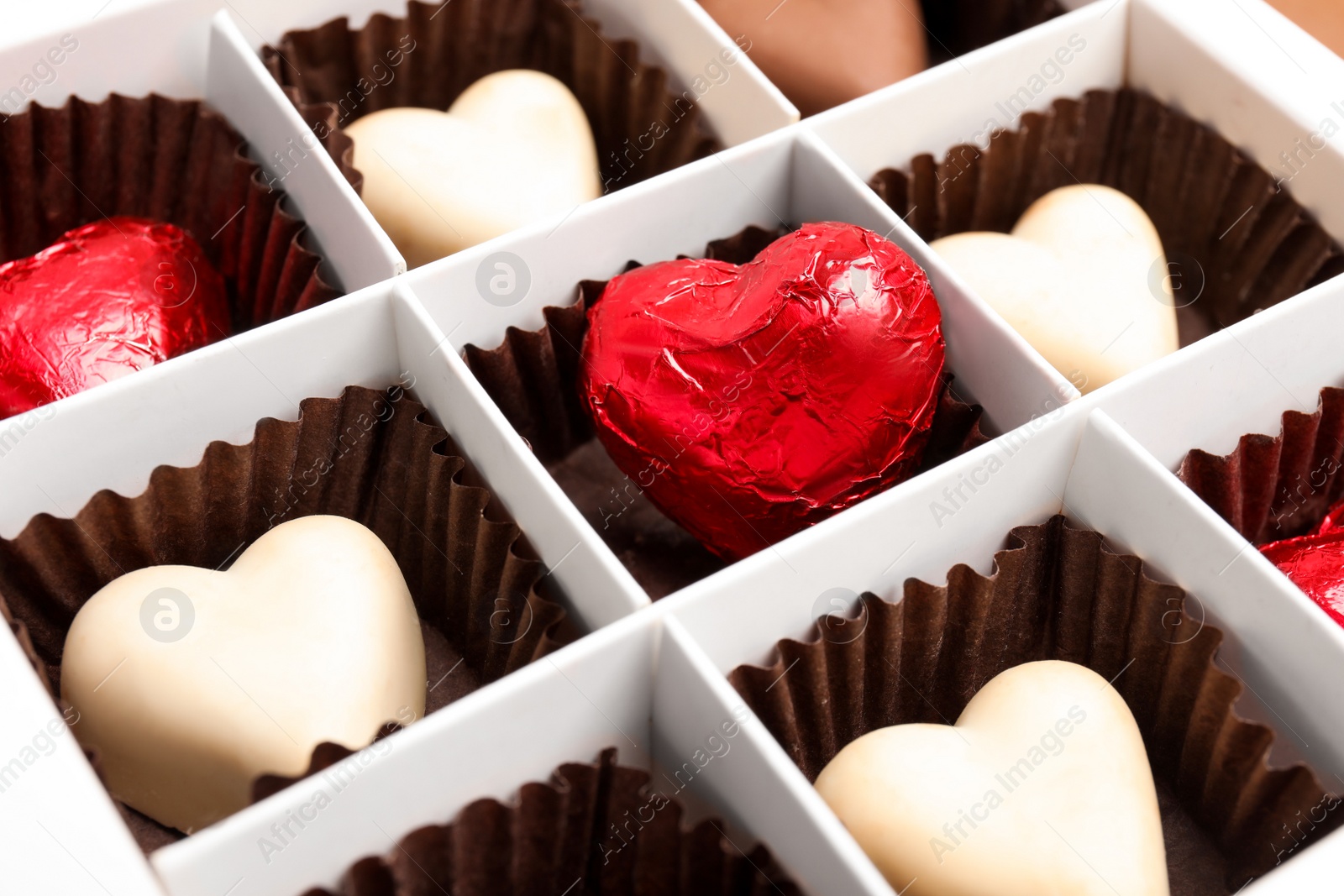 Photo of Tasty heart shaped chocolate candies in box, closeup. Valentine's day celebration