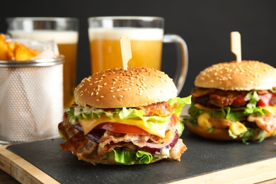 Photo of Tasty burgers with bacon served on board