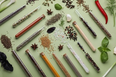 Photo of Flat lay composition with various spices, test tubes and fresh herbs on pale green background