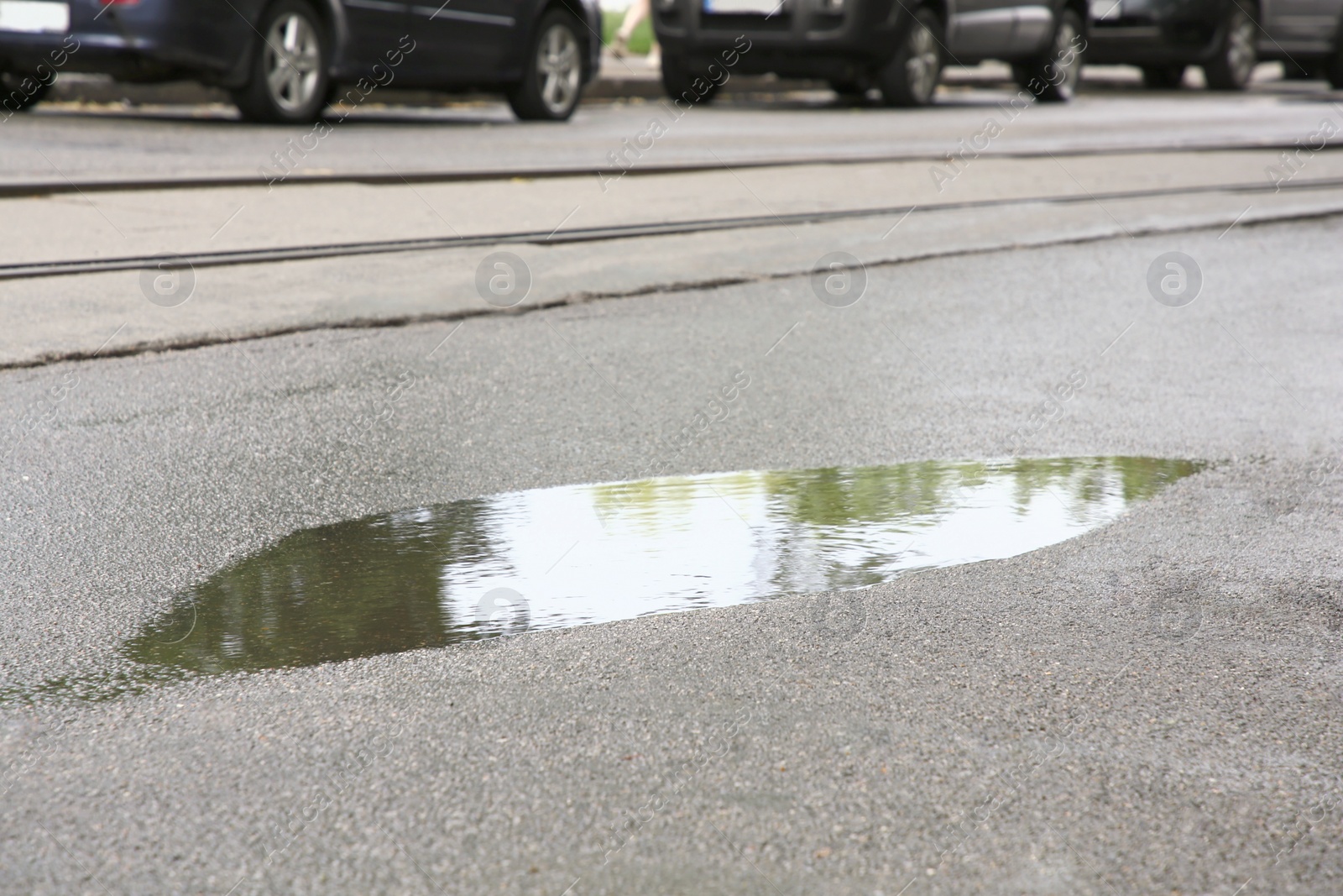 Photo of View of puddle on sidewalk near road. Rainy day