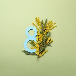 Photo of 8 March greeting card design with beautiful mimosa flowers on green background, flat lay