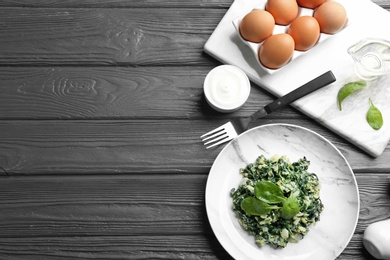 Photo of Tasty cooked spinach served on dark wooden table, flat lay with space for text. Healthy food