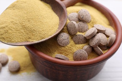 Beer yeast powder and pills on white table, closeup