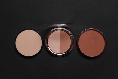 Different face powders on black background, flat lay