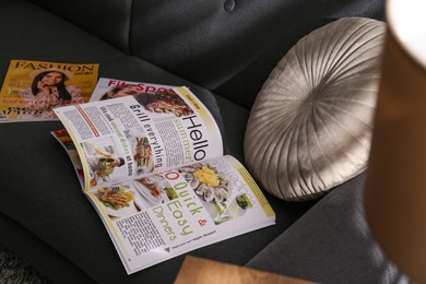 Different lifestyle magazines and pillow on comfortable sofa