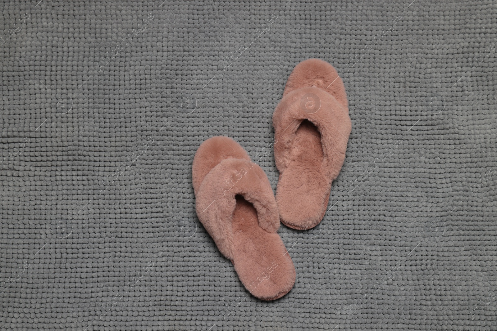 Photo of Slippers on soft grey bath mat, flat lay