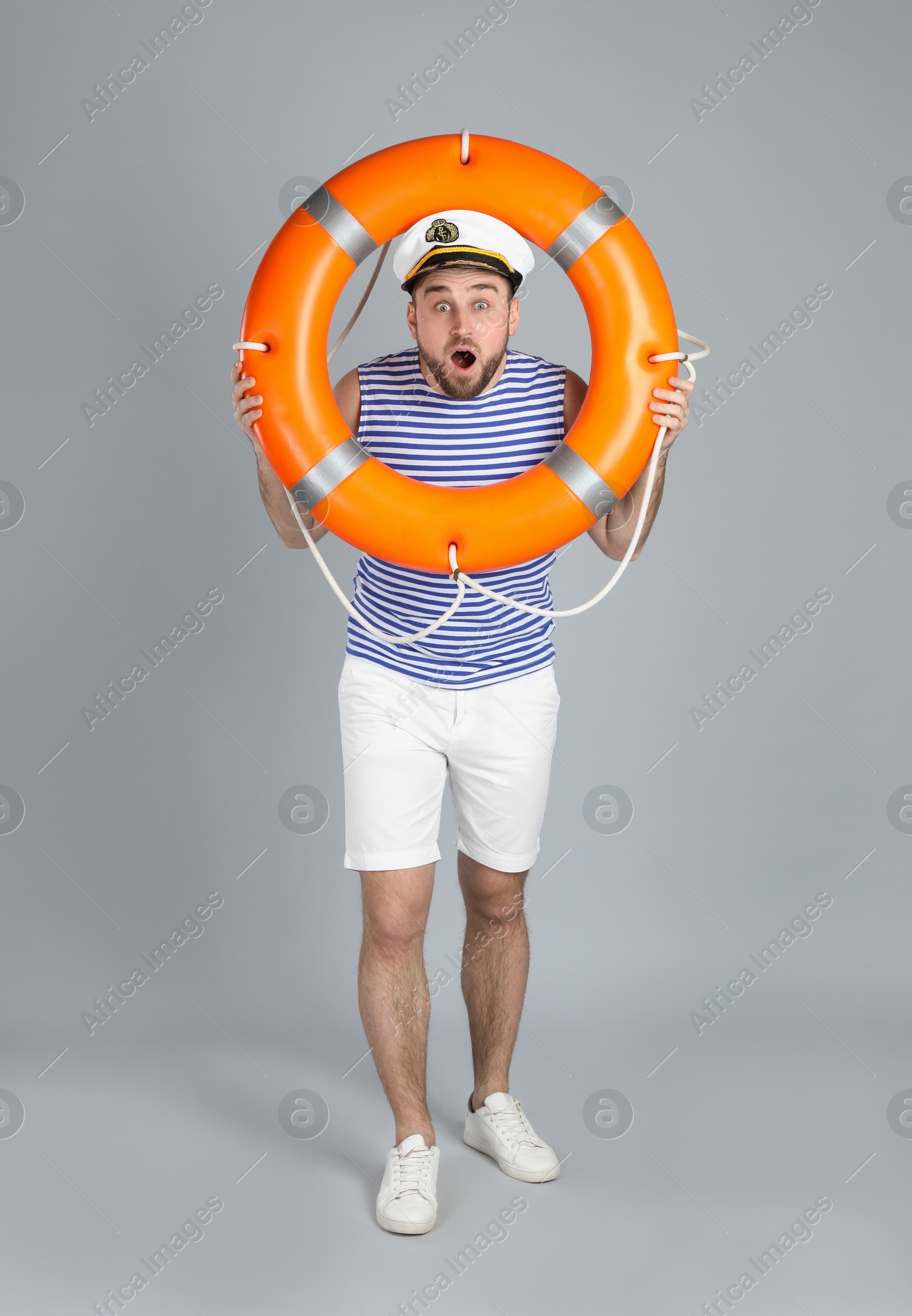 Photo of Emotional sailor with ring buoy on light grey background