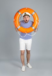 Photo of Emotional sailor with ring buoy on light grey background