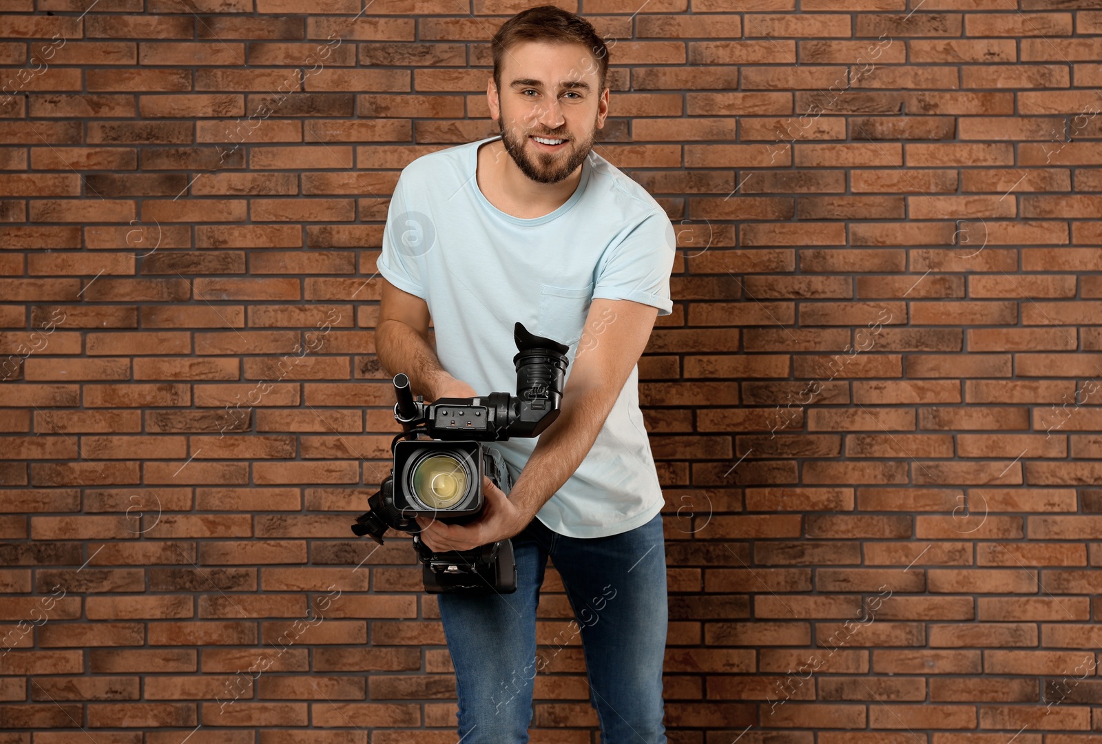 Photo of Operator with professional video camera near brick wall