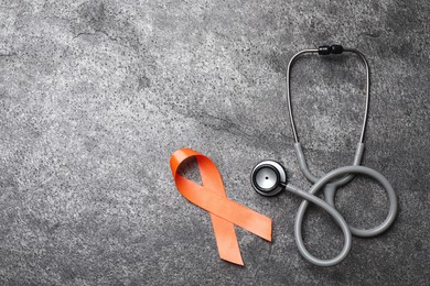 Orange ribbon and stethoscope on grey table, flat lay with space for text. Multiple sclerosis awareness