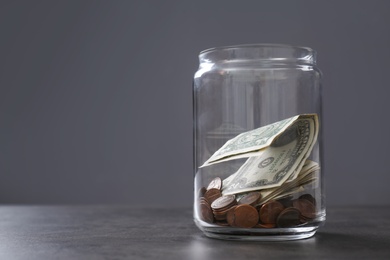 Photo of Donation jar with money on table against grey background. Space for text