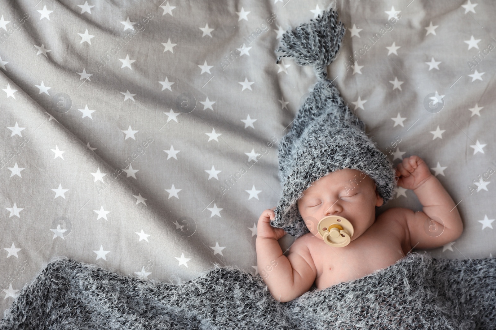 Photo of Cute newborn baby in warm hat sleeping on bed, top view. Space for text