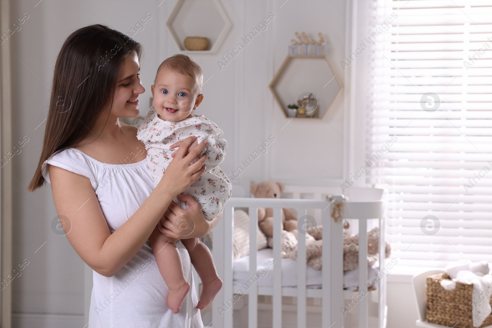 Photo of Happy young mother with her baby daughter in nursery. Space for text