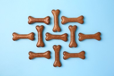 Photo of Bone shaped dog cookies on light blue background, flat lay
