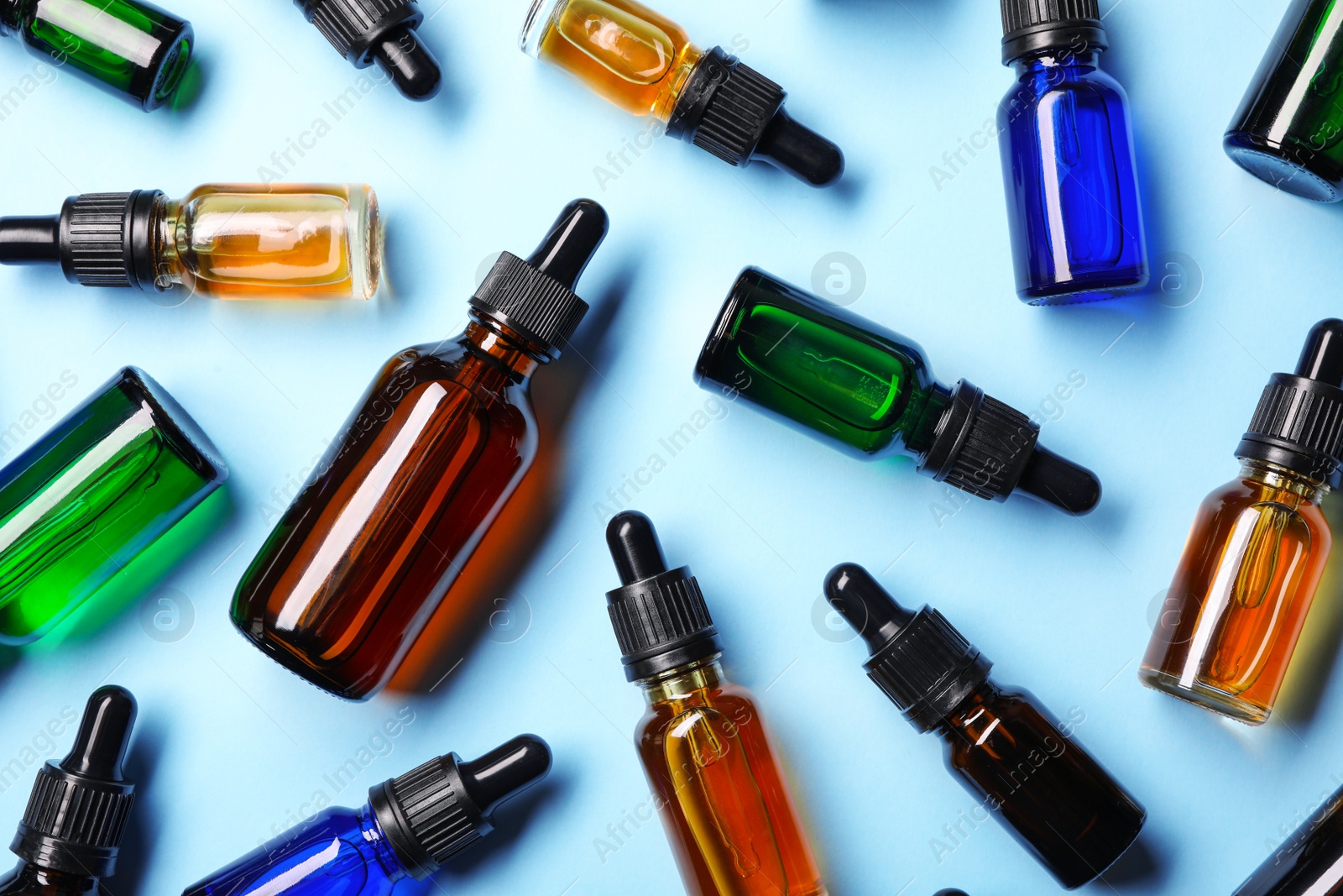 Photo of Flat lay composition with cosmetic bottles of essential oils on color background