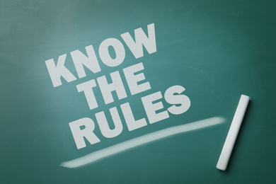 Image of Phrase Know the rules and piece of chalk on greenboard, top view