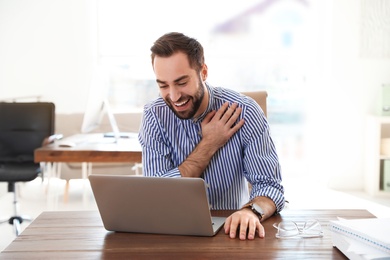 Photo of Young man using video chat on laptop in home office