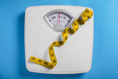 Photo of Weight loss concept. Scales and measuring tape on blue background, top view