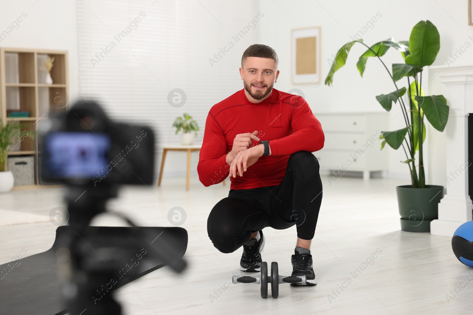 Photo of Trainer recording fitness lesson on camera at home