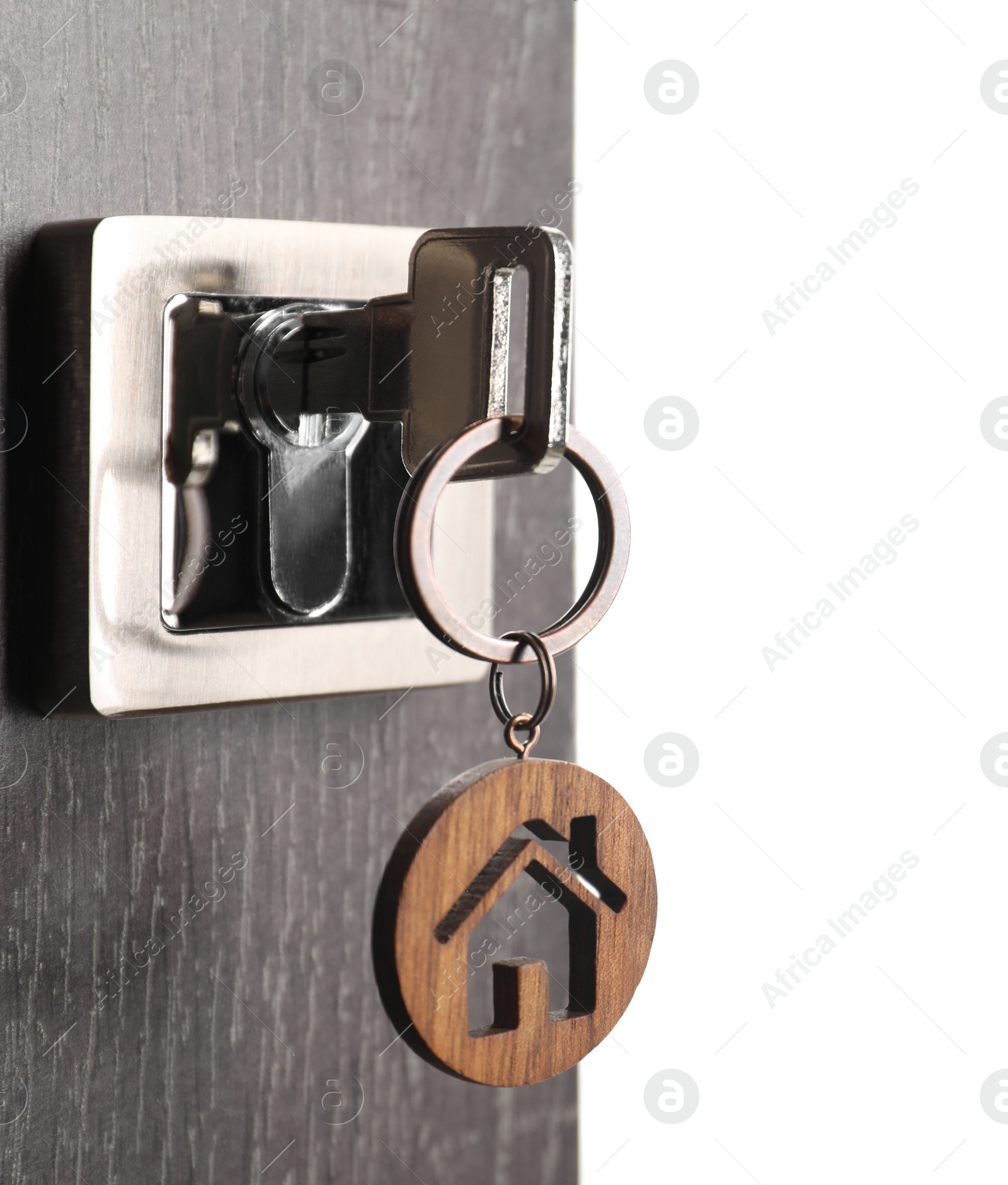 Photo of Mortgage and real estate. Open door with key and house shaped keychain on white background, space for text