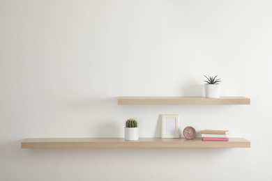 Wooden shelves with books and decorative elements on light wall