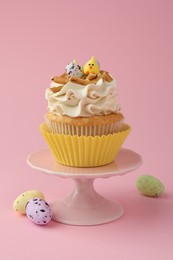 Tasty Easter cupcake with vanilla cream and candies on pink background