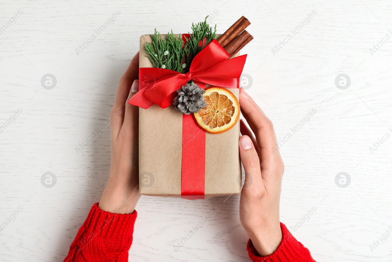 Photo of Woman wrapping Christmas gift at white wooden table, top view