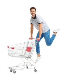 Young man with empty shopping cart on white background